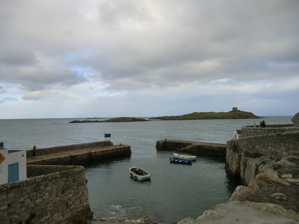 Coliemore Harbour in Dalkey with small boats, stone piers and Dalkey Island in the distance.