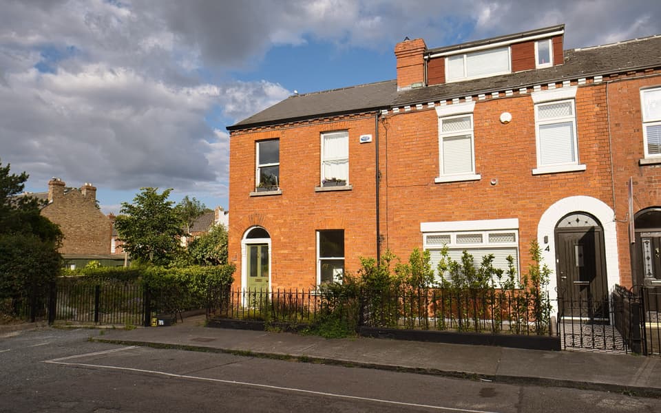 A terrace of red-brick houses with small front gardens on Woodville Road, Drumcondra.