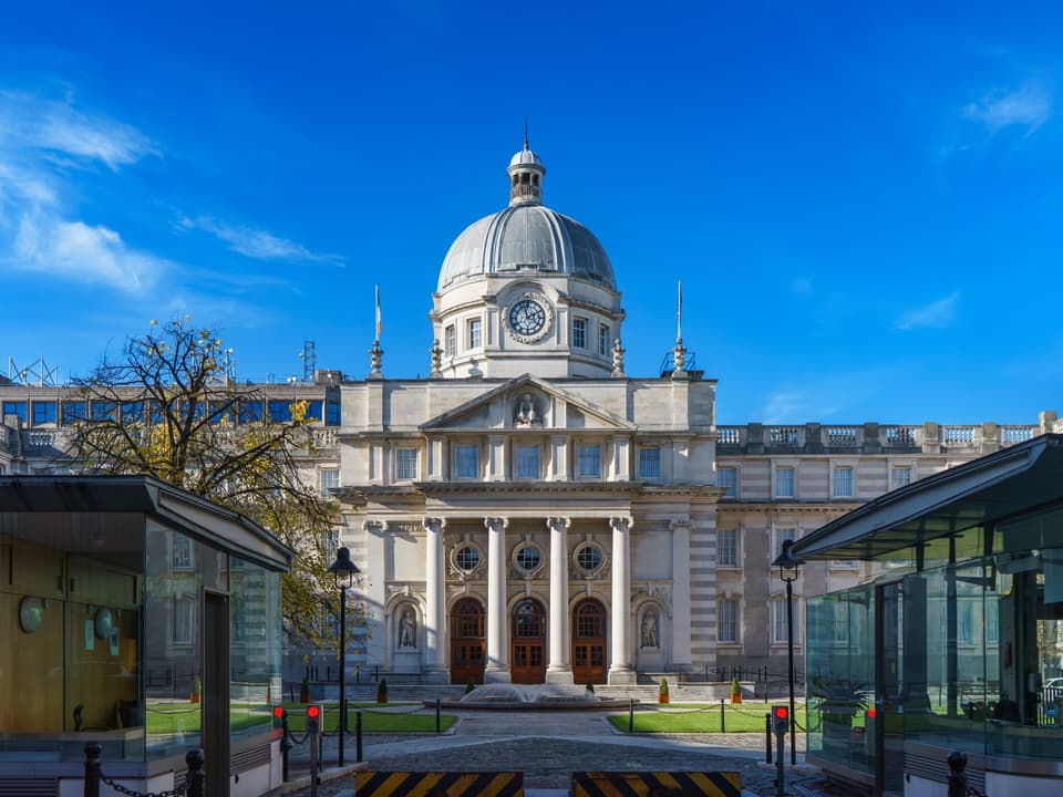 The domed front of Government Buildings on Merrion Street, Dublin, under a blue sky.