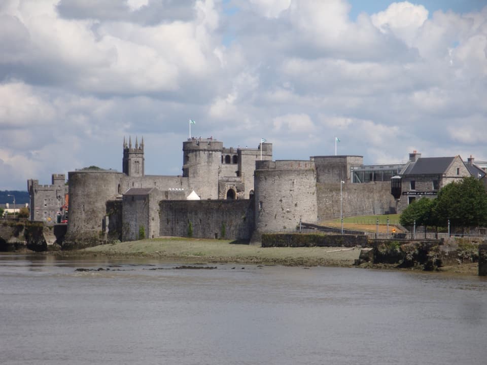 King John's Castle on the bank of the River Shannon in Limerick under a cloudy sky.