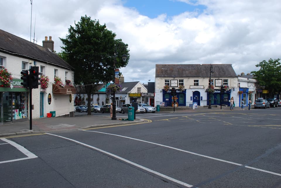 The centre of Malahide village, with painted shopfronts and hanging baskets around a road junction.