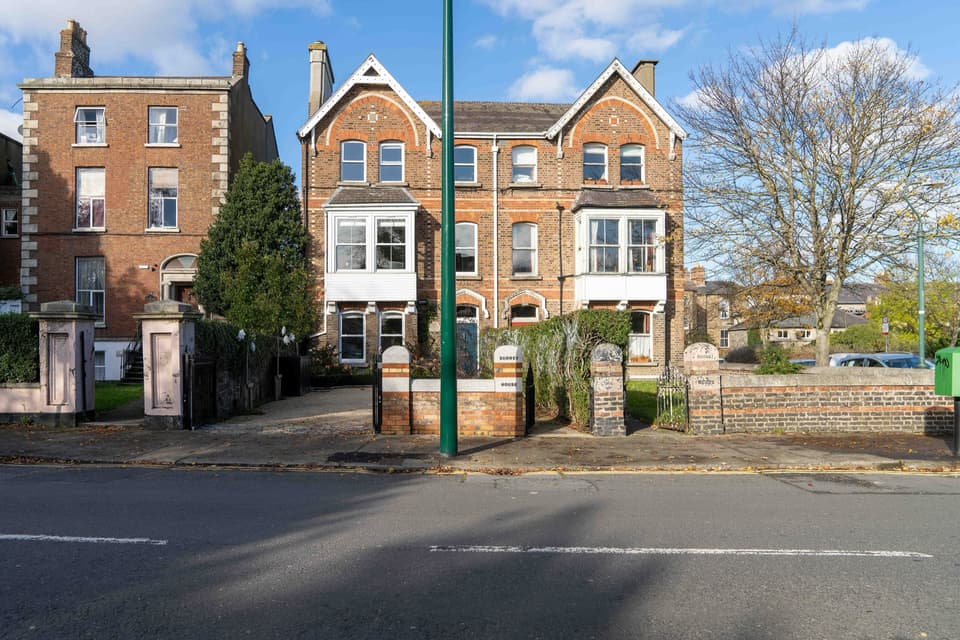 A pair of Victorian red-brick houses behind gate piers and railings on Leinster Road, Rathmines.