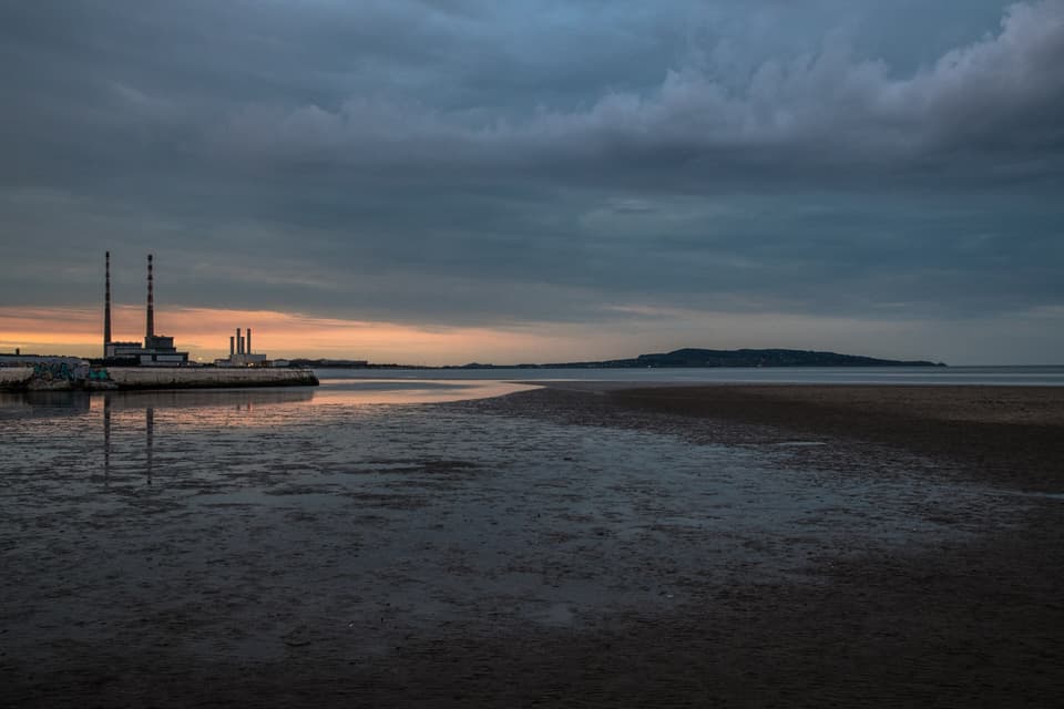 Sandymount Strand at low tide at dusk, with the Poolbeg chimneys and Howth Head on the horizon.